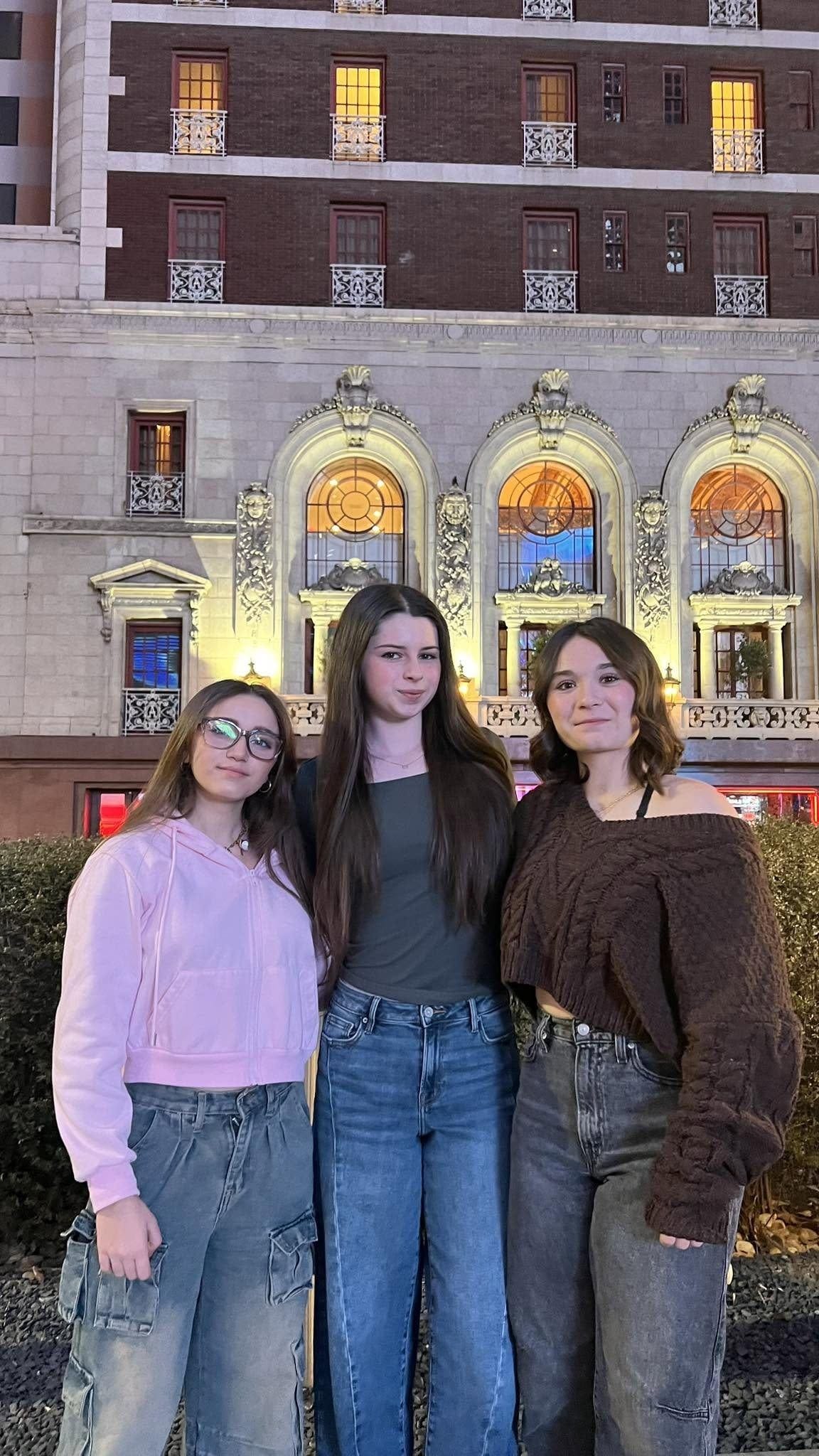 Angelina, Scarlett, and Annabella standing outside one of Texas' most haunted hotels at night